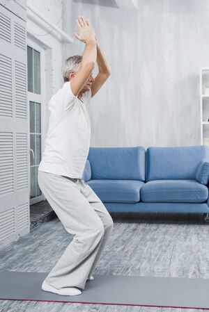 Sporty-elderly-man-practicing-yoga-indoors-min.jpg