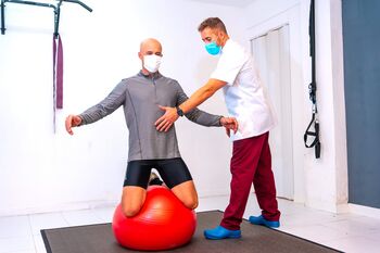 Client-balancing-red-ball-assisted-by-physiotherapist-with-face-mask-physiotherapy-with-protective-measures-coronavirus-pandemic-covid19-osteopathy-sports-quiromassage-min (1).jpg